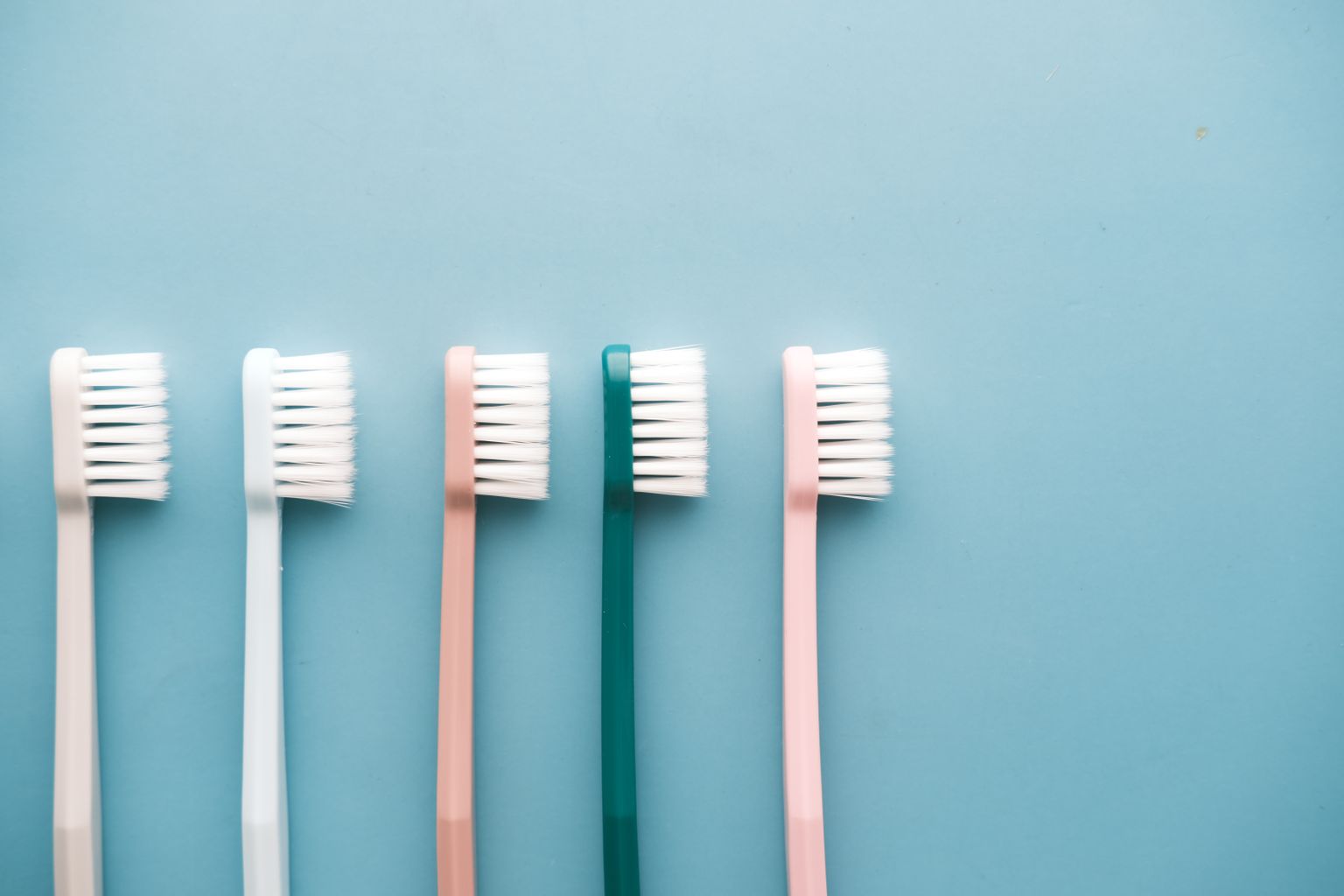 A row of five colorful toothbrushes arranged on a blue background, perfect for dental care themes.